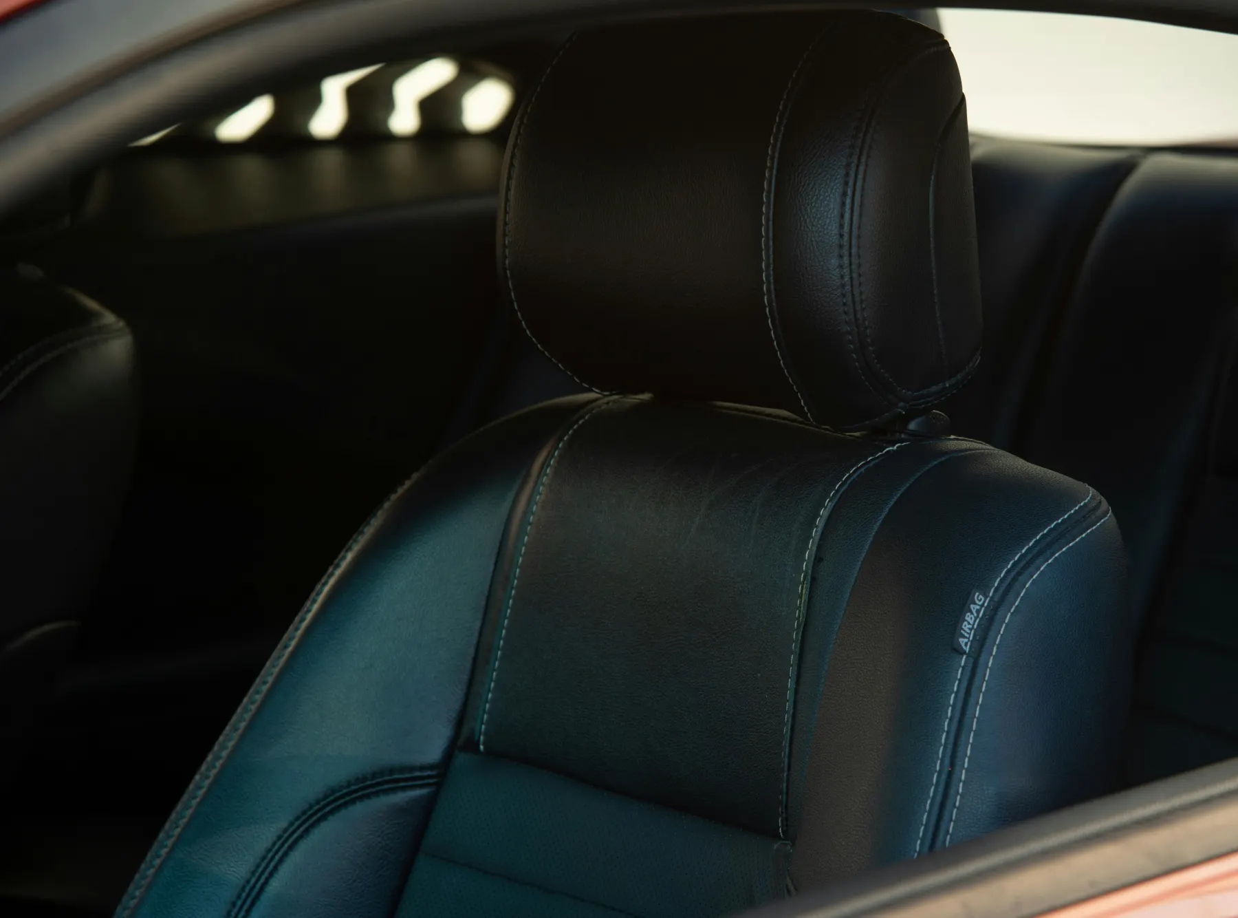 Black leather car seat with hand-stitched bolster